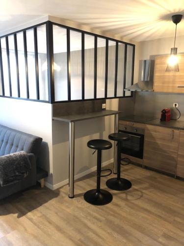 une cuisine avec deux tabourets de bar dans une pièce dans l'établissement Cocon Cosy Nancy centre, à Nancy
