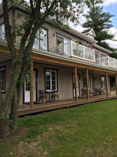 a large house with a balcony with tables and chairs at Orange Bistro in Baie-Saint-Paul