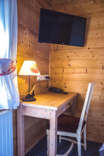 a wooden desk with a lamp and a tv on a wall at Le Relais Du Mont Blanc in Magland