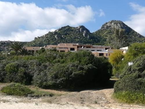 a building on a hill with mountains in the background at Home Beach Costa Rey in Costa Rei
