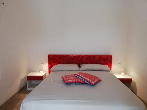 two red pillows on a white bed with two lamps at Fiore di Cappero in Ostuni