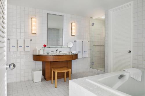 a bathroom with a sink and a mirror and a tub at Halekulani - NO RESORT FEE in Honolulu