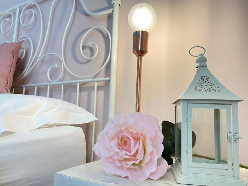 a pink flower and a lantern on a table next to a bed at Ai Raggi di Sole in Lecce