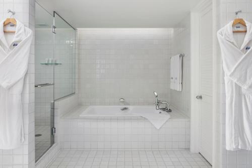 a white bathroom with a tub and a shower at Halekulani - NO RESORT FEE in Honolulu