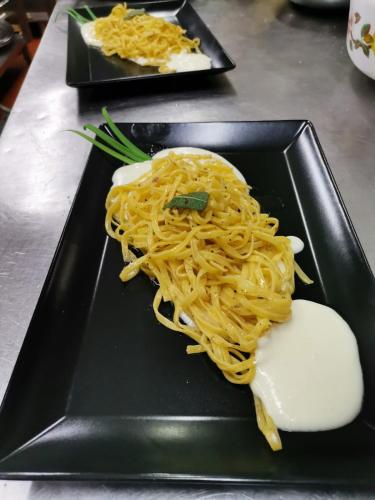 a black plate with noodles and other foods on it at Casa Oliva borgo del Benessere Olistico in Bargni