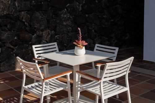 a white table with four chairs and a vase with flowers at Nazaret Mansion in Costa Teguise