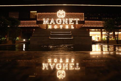 a hotel sign in front of a building at night at Magnet Hotel in Kannur