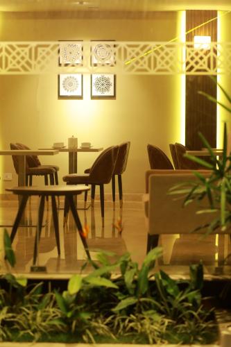 a dining room with tables and chairs and plants at Magnet Hotel in Kannur
