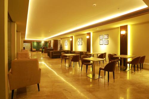 a restaurant with tables and chairs in a lobby at Magnet Hotel in Kannur