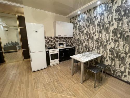 eine Küche mit einem Kühlschrank und einem Tisch mit Stühlen in der Unterkunft AK-BULAK TOWN Apart in Astana