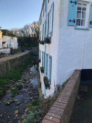 a white house with a window and a brick wall at Quirky Lyme Regis Apartment Near Beach in Lyme Regis