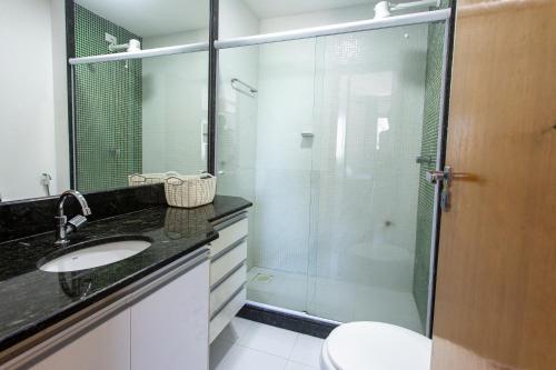 a bathroom with a glass shower and a sink at Praia Dourada SUÍTE ITAPARICA in Vila Velha