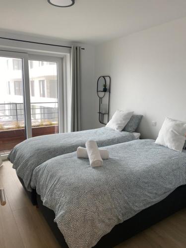 een slaapkamer met 2 bedden en witte handdoeken. bij Lichtrijk 2-slaapkamerappartement met zeezicht en gratis parking in Oostende