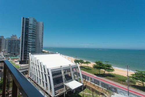 einen Balkon mit Blick auf ein Gebäude und den Strand in der Unterkunft SUÍTE ITAPARICA Praia Dourada in Vila Velha