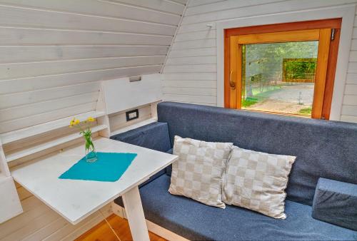 a small table and a blue couch in a tiny house at Kamp Koren Kobarid in Kobarid