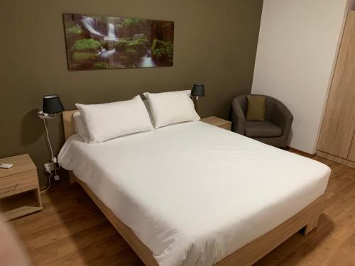 una camera con un grande letto bianco e una sedia di Apartment 14 a San Pawl il-Baħar