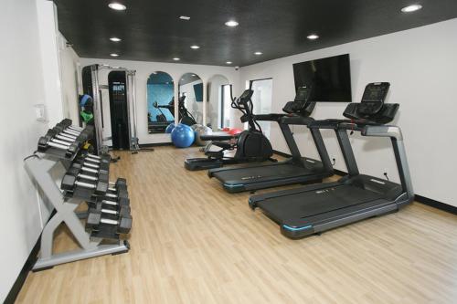 a gym with several tread machines and a tv at La Quinta by Wyndham Des Moines West Clive in Clive