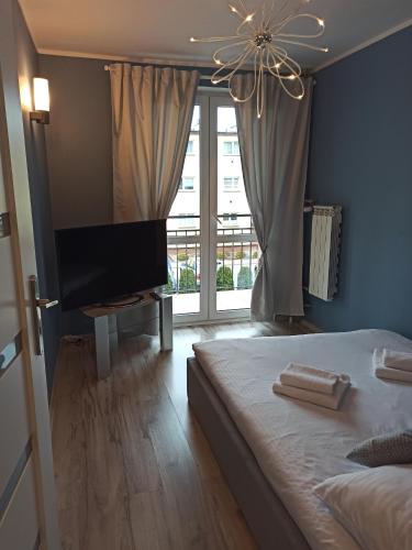 ein Schlafzimmer mit einem Bett und einem Flachbildfernseher in der Unterkunft Na Sadowej in Grodzisk Mazowiecki