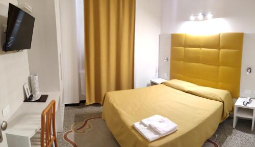 a hotel room with a yellow bed and a television at Hotel Villa Costa in Celle Ligure