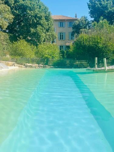 a pool of blue water with a building in the background at La Bastide des Grands Chênes in Lambesc