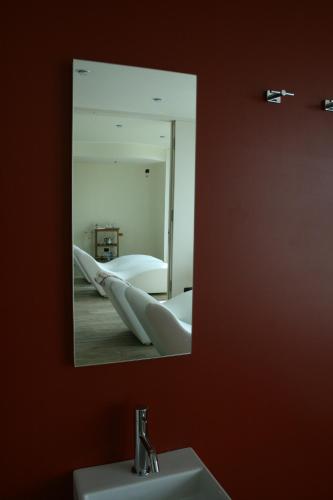 a mirror reflecting a bathroom with a sink and a bed at Azienda Agrituristica Calronche in Refrontolo