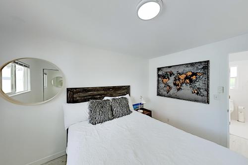 a white bedroom with a bed and a mirror at Beach House Oasis in Des Moines