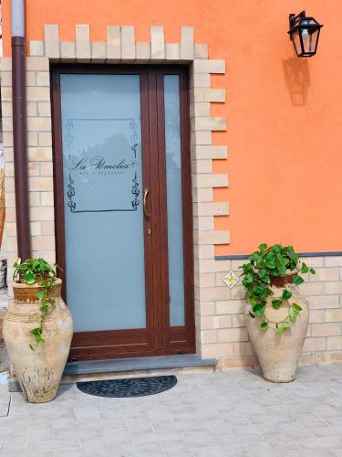 a door with two potted plants in front of a building at La Pomelia B&b Sofia in Trappitello
