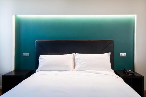 a bed with a black headboard and white pillows at SIRIOHotel in Dormelletto