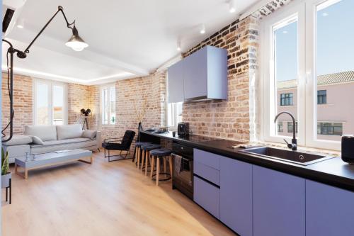 una cucina e un soggiorno con un muro di mattoni di Vailato Loft Suites a Città di Corfù