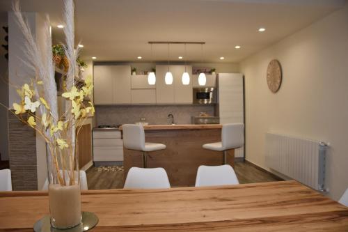 cocina con mesa de madera y sillas blancas en I Mori APARTAMENT, en Ragalna