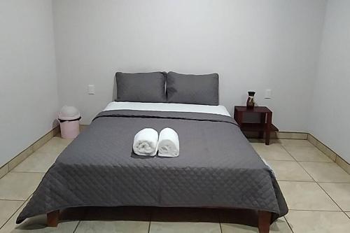 a bedroom with a bed with a pair of shoes on it at Hospedaje Rio Celeste Katira, Habitación privada in San Rafael
