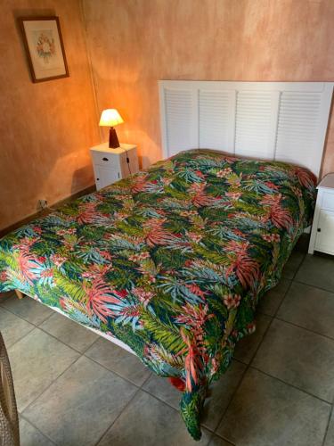 uma cama com um edredão colorido num quarto em La maison sur la place em Aigues-Mortes