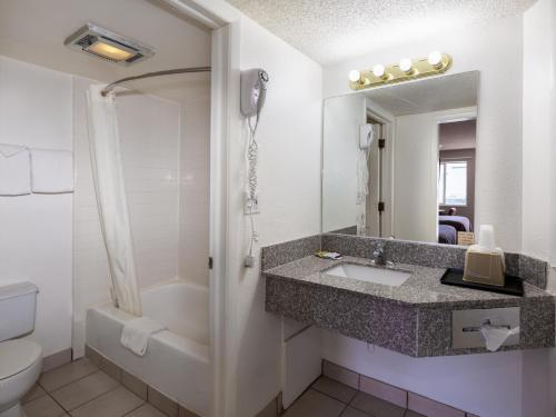 a bathroom with a sink and a toilet and a mirror at Bardmoor Suites in Cedar City