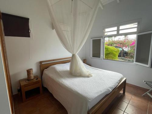 a bedroom with a white bed with a window at VILLA STE MARTHE avec piscine, grande terrasse, jardin intime et citerne d'eau in Saint-François