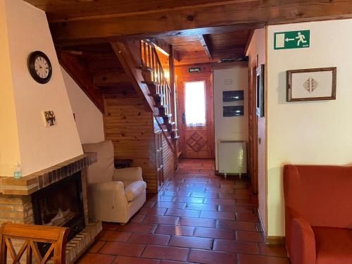 a living room with a fireplace and a clock on the wall at La Casita de la Sierra Cercedilla in Cercedilla