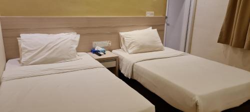 two beds in a hotel room with white sheets and pillows at Star Tree Homestay -Contactless Self Check in in Kuantan