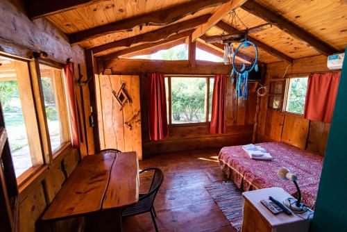 a room with a bed and a table in a cabin at Complejo Flores Azules in Olta