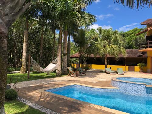 uma piscina com rede de descanso e um resort em Jardim Boêmio em Cananeia