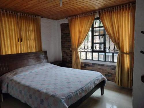 1 dormitorio con cama y ventana grande en Cabaña Villa Gabriela, en Paipa