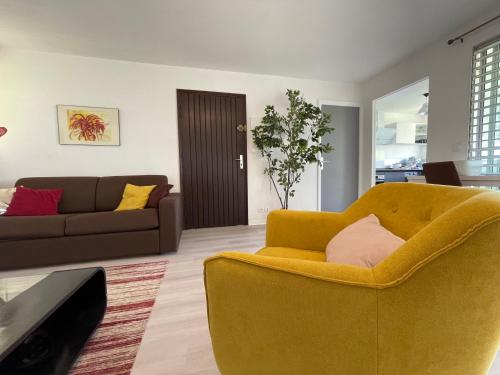 a living room with a yellow chair and a couch at Jarry Entre Chien et Loup in Baie-Mahault