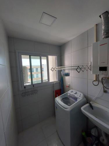 ein kleines Bad mit einem Waschbecken und einer Waschmaschine in der Unterkunft Lindo Apartamento no Muro Alto Condomínio Clube in Ipojuca