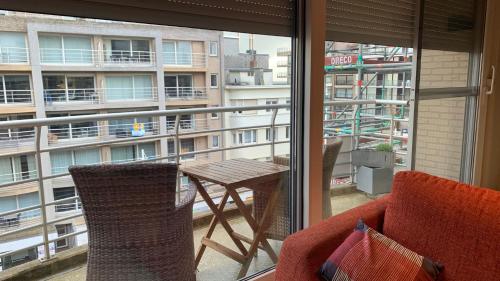 einen Balkon mit einem Tisch und Stühlen sowie Blick auf ein Gebäude in der Unterkunft Appartement “zon en vakantie aan zee” in Koksijde