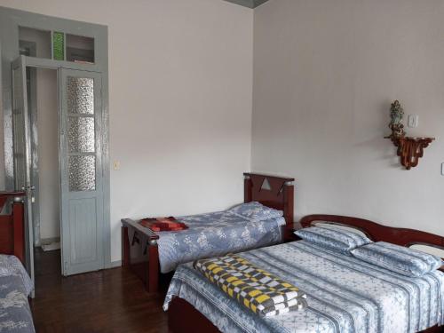 a bedroom with two beds and a door to a room at Pousada Gameleira in Diamantina