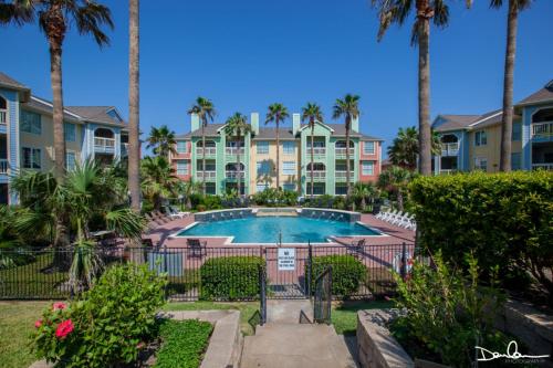 a resort with a swimming pool and palm trees at Island Getaway in Galveston