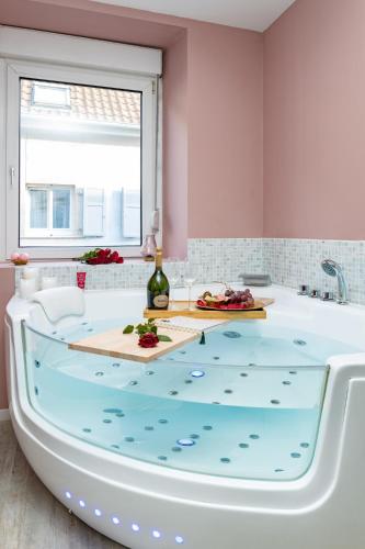 a bath tub with a table with a bottle of wine at @Romantic Suite & Spa @Jacuzzi @ Parking gratuit @ in Mulhouse