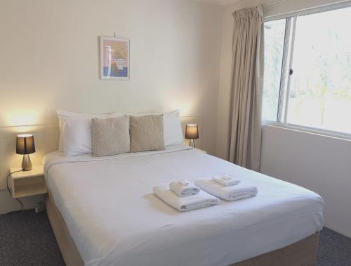 a bedroom with a white bed with towels on it at Bay of Palms in Gold Coast