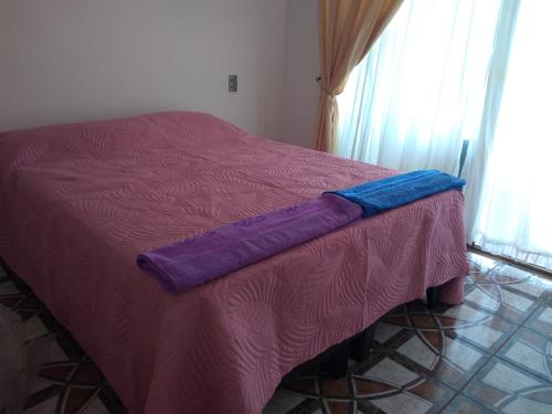 a bed with a purple blanket on top of it at Acogedor apartamento vista al mar in Iquique