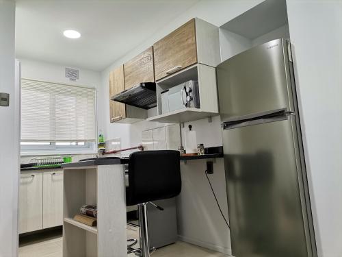 a kitchen with a stainless steel refrigerator and a table at Apartasuite Altos del Bosque in Punta Arenas