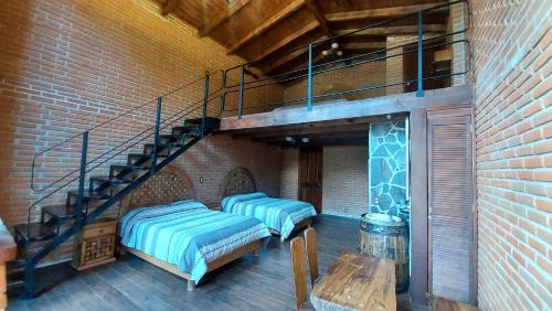 a room with two beds and a spiral staircase at Cabañas Doña Anita in San Miguel Regla