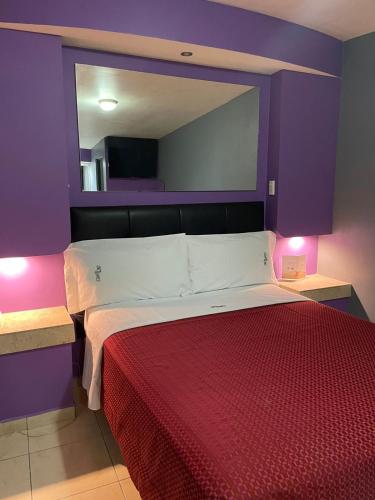 a bedroom with a large bed with purple walls at Motel Las Dunas in Mexicali